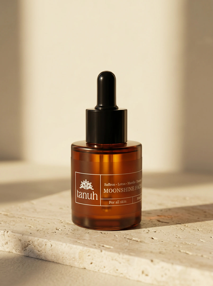 Tanuh Moonshine face oil — amber glass bottle with black dropper on travertine stone, saffron kumkumadi night oil, 30ml